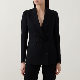 Model wearing Akris Punto black double-breasted blazer with peak lapels and six-button front, styled with matching black trousers.
