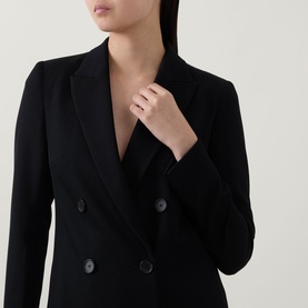 Model wearing Akris Punto black double-breasted blazer with notch lapels and dark buttons, styled with black top underneath.