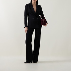 Model wearing Akris Punto black double-breasted blazer with wide-leg trousers, styled with a burgundy clutch bag and pointed heels.
