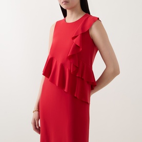 Model wearing Akris Punto red sleeveless dress with asymmetric ruffle detail, styled with a gold bangle bracelet.