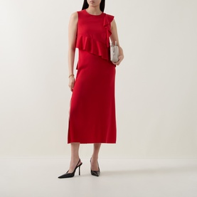 Model wearing Akris Punto red sleeveless midi dress with ruffle detail and side slit, styled with black heels and silver clutch bag.