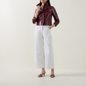 Model wearing Akris Punto pomegranate patent leather cropped jacket with white wide-leg trousers and strappy heeled sandals.