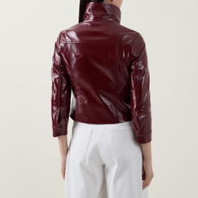 Model wearing Akris Punto pomegranate patent leather jacket, rear view, styled with white wide-leg trousers