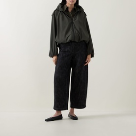 Model wearing Akris Punto olive parka with zip front and hood, styled with black wide-leg trousers and flat mules.