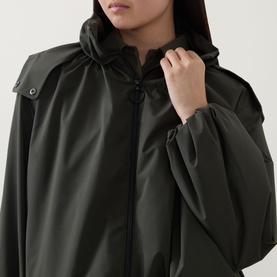 Model wearing Akris Punto olive parka, close-up showing ruched sleeves, hooded neckline and zip fastening detail