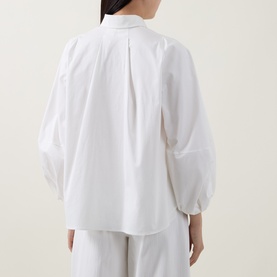 Model wearing Akris Punto cream shirt, back view, with voluminous balloon sleeves, pleat detail, and wide-leg trousers