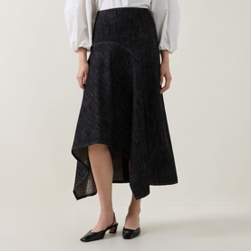 Model wearing Akris Punto black denim asymmetric hem midi skirt, styled with a white blouse and black mule heels.