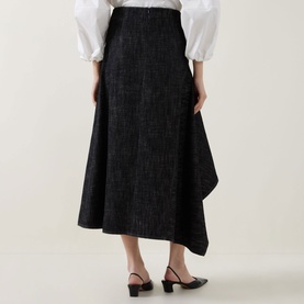 Model wearing Akris Punto black denim asymmetric midi skirt, styled with a white blouse and black slingback heels, rear view.