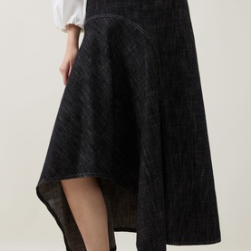 Model wearing Akris Punto Black Denim skirt with asymmetric high-low hem and contrast stitching, styled with a white blouse.