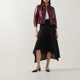 Model wearing Akris Punto Black Denim skirt with asymmetric hem, styled with a burgundy patent jacket and black flats.