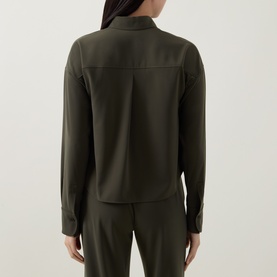 Model wearing Akris Punto olive shirt, rear view, long sleeves with cuffs, styled with matching olive trousers