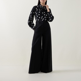 Model wearing Akris Punto black-cream floral print shirt with wide-leg black trousers, full-length front view