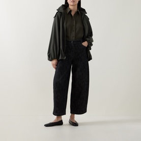 Model wearing Akris Punto Black Denim trousers, wide-leg cropped fit, styled with olive jacket and black ballet flats.