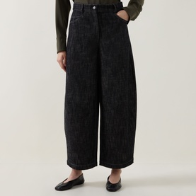 Model wearing Akris Punto Black Denim wide-leg trousers, styled with a dark knit top and black flat loafers.