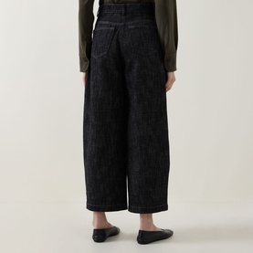 Model wearing Akris Punto black denim wide-leg trousers, rear view, styled with an olive top and black flat shoes.