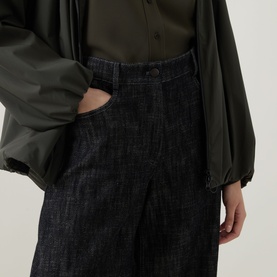 Model wearing Akris Punto Black Denim trousers, wide-leg cut, styled with an olive green satin blouse and jacket.