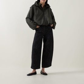Model wearing Akris Punto Black Denim trousers, wide-leg cropped fit, styled with an oversized dark shirt and flat mules.