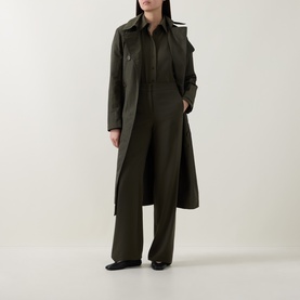 Model wearing Akris Punto olive wide-leg trousers, styled with a matching olive shirt and long khaki trench coat, black flats.