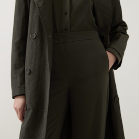 Model wearing Akris Punto olive trousers with wide-leg cut, styled with a matching olive button-front coat.