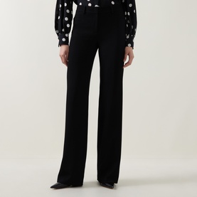 Model wearing Akris Punto black wide-leg trousers with high waist, styled with a polka dot blouse and black heels.