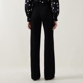Model wearing Akris Punto black wide-leg trousers, rear view, styled with a polka dot blouse with puffed sleeves.
