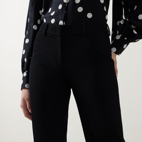Model wearing Akris Punto black tailored trousers with a black and white polka dot blouse.