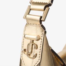 Jimmy Choo gold metallic leather bag close-up showing JC logo charm and gold-tone buckle strap detail