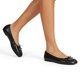 Model wearing Steve Madden black leather ballet flats with small bow detail and flat sole, styled with bare legs.