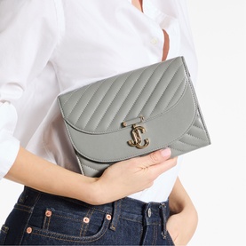Model carrying Jimmy Choo bag in dove grey quilted leather with shiny gold JC logo clasp closure