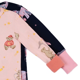 Close-up of pink and navy children's sleepsuit with teddy bear and bunny print, pink cuffed sleeves detail visible