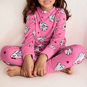 Model wearing Chelsea Peers Sleepover Ghost bright pink pyjama set with all-over ghost and heart print, long sleeves and trousers.