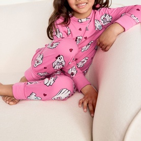 Model wearing Chelsea Peers Sleepover Ghost bright pink pyjama set with all-over ghost and heart print, long sleeves and elasticated ankles.
