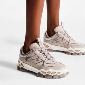 Model wearing Jimmy Choo trainers in taupe leather and suede with chunky ridged sole and lace-up fastening