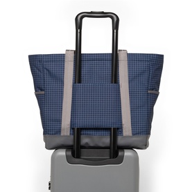 Herschel Tote in Grid Naval Academy, navy blue check fabric with grey handles, shown mounted on a grey rolling suitcase trolley handle.