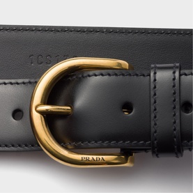 Prada Accessories black leather belt with gold-tone buckle and embossed Prada logo detail, close-up view.