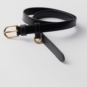 Prada Accessories black leather belt with gold-tone buckle and ring detail, coiled on a flat surface