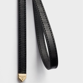 Prada Accessories black leather belt with gold-tone triangular logo tip, close-up detail shot