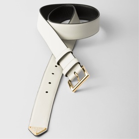 Prada Accessories white leather belt with gold-tone buckle and branded tip, reversible black lining, coiled flat on grey surface.