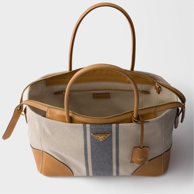 Prada Accessories neutral canvas tote bag with blue stripe detail, tan leather trim and handles, gold-tone hardware, and detachable shoulder strap.