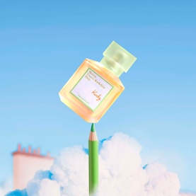 Maison Francis Kurkdjian EDT in amber glass bottle with mint green cap, balanced on a green pencil against a blue sky with clouds.