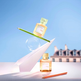 Maison Francis Kurkdjian EDC fragrance duo displayed on paper shapes with pastel tones and Parisian building backdrop