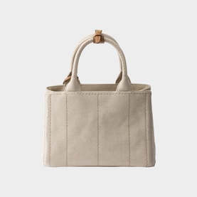 Prada Accessories neutral canvas tote bag with structured panels, tan leather top handle detail, and open top