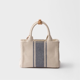 Prada Accessories neutral canvas tote bag with navy stripe detail, tan leather top handles and trim, structured silhouette