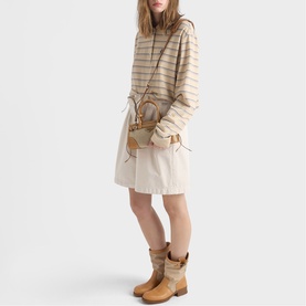 Model carrying Prada Accessories neutral bag, styled with striped cream knit jumper, mini skirt and tan Western ankle boots.