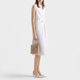 Model carrying Prada Accessories powder tote bag with top handles and silver-tone hardware, styled with white sleeveless dress and silver heels