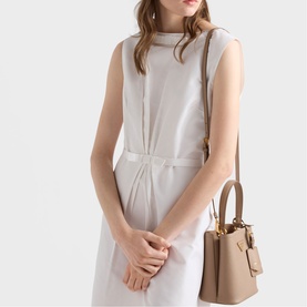 Model carrying Prada Accessories powder tote bag with gold-tone hardware and short top handles, styled with a grey sleeveless dress