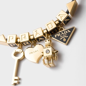 Prada gold-tone charm bracelet featuring logo cube links, triangular plaque, key, heart, and lantern charms