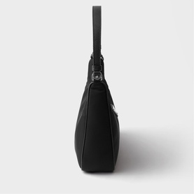 Black structured shoulder bag with short top handle, silver-tone hardware, and zip fastening, shown from side profile