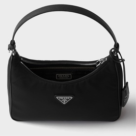 Prada Re-Edition nylon mini bag in black with silver-tone triangle logo plaque, zip top closure, and short top handle.