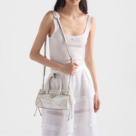 Model carrying Prada Accessories white structured mini bag with silver hardware and crossbody strap, styled with white ribbed top and midi skirt